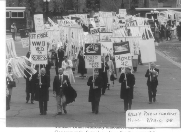 Protesters in business dress walk with signs and banners