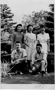 Three young women and two young men standing outside posing for a photo