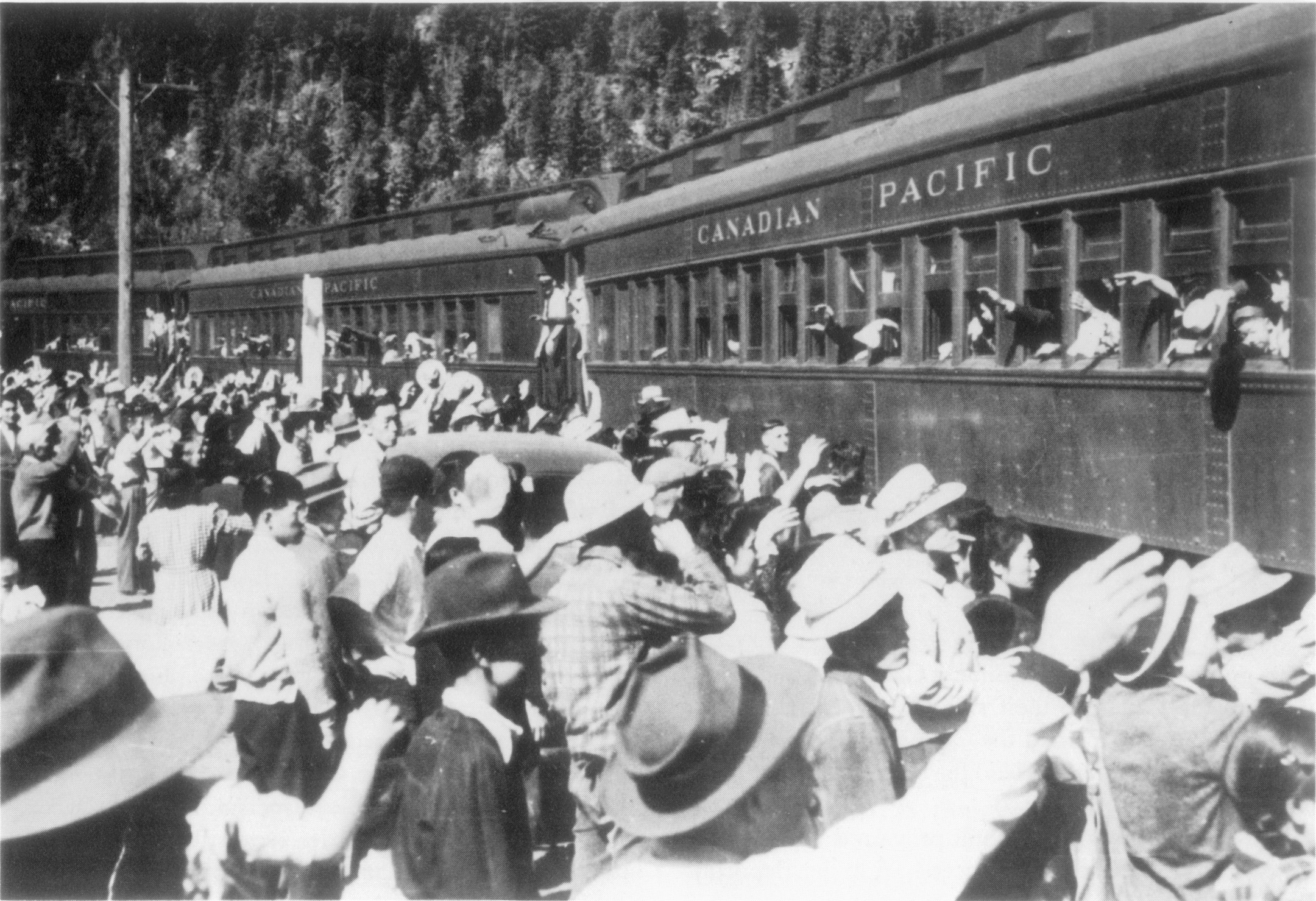 Large group of people gathered alongside a train waving goodbye