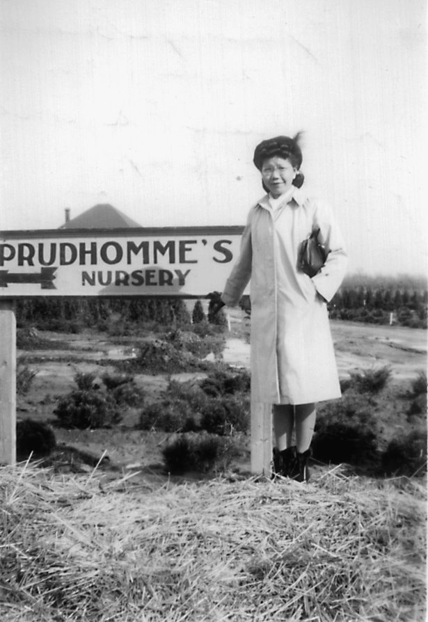 Woman standing in front of a sign which reads "Prudhomme's Nursery"