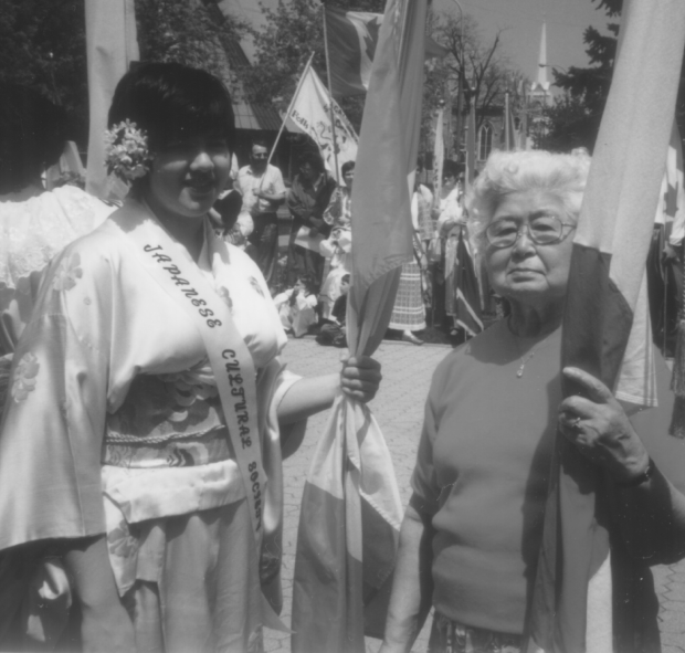 Young woman and elderly woman standing together holding flags