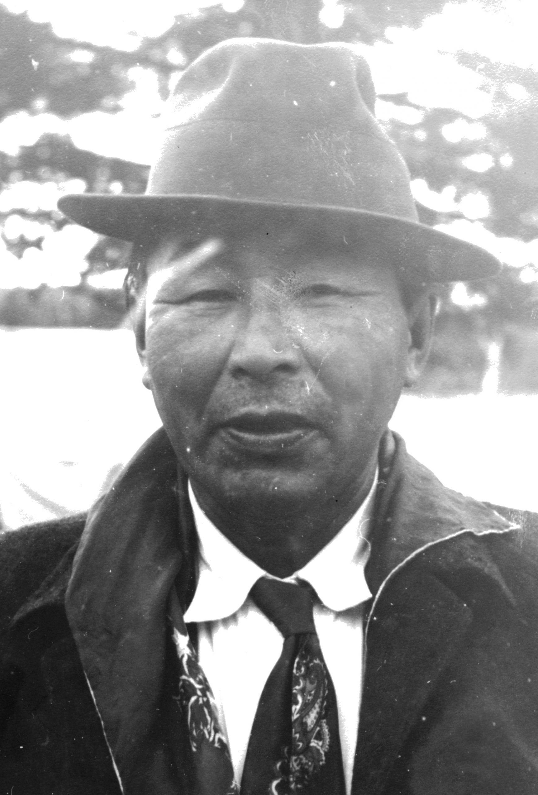 Close-up portrait of a former Lac Simon chief. He is wearing a hat, shirt, tie and jacket. Black and white picture.
