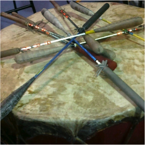 Large drum used in a pow wow with several sticks left on top. Picture in color.