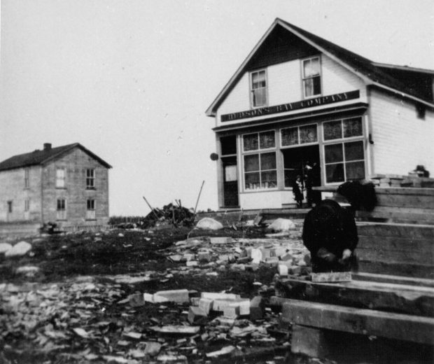 Black and white photo of the Hudson's Bay Company Store in Senneterre, a small house with two people in front.