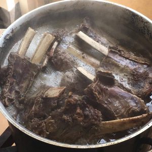 Moose ribs are boiled in a large pot. Picture in color.