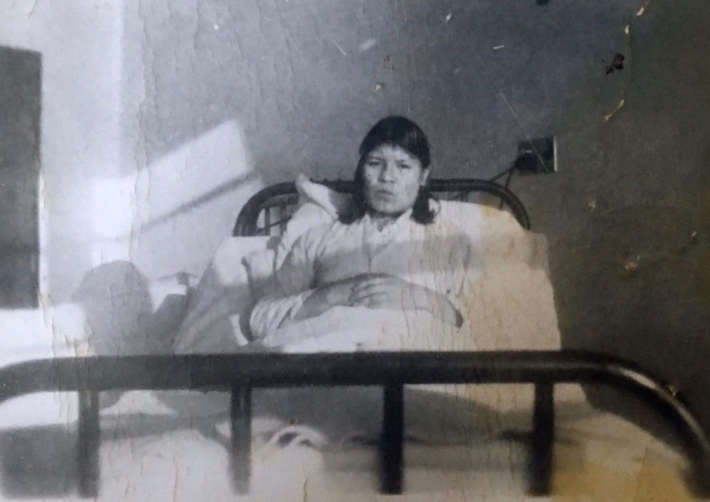 An anicinabe woman sitting in her bed at the sanatorium in St-Jean de Macamic. Black and white picture.