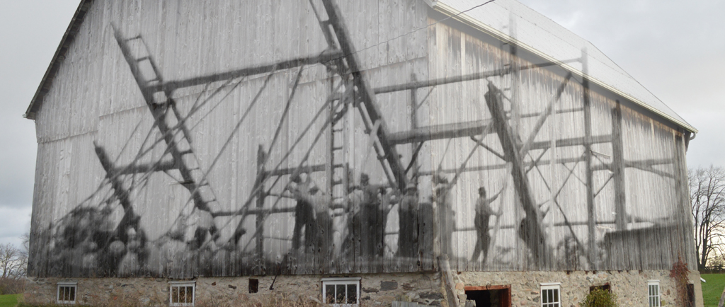 A contemporary photograph of a bank barn with a superimposed image of the work bee that raised it.