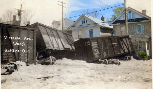A black and white photograph of a train wreck superimposed on contemporary image of houses.