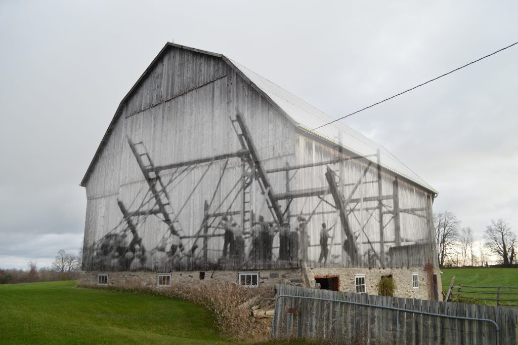 A contemporary photograph of a barn with a superimposed image of the work bee that raised it.