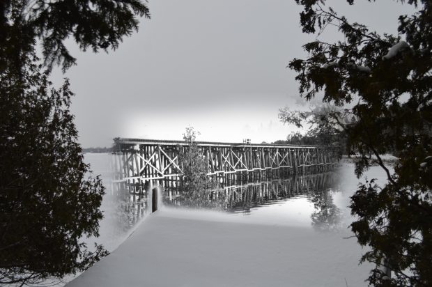 An image of a wooden railroad bridge fades into a contemporary image wherein the bridge is gone.