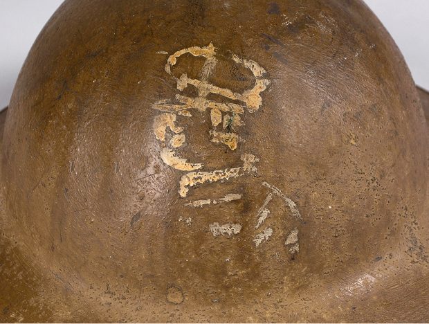 A brown helmet with a very faded painted image of a soldier painted on it.
