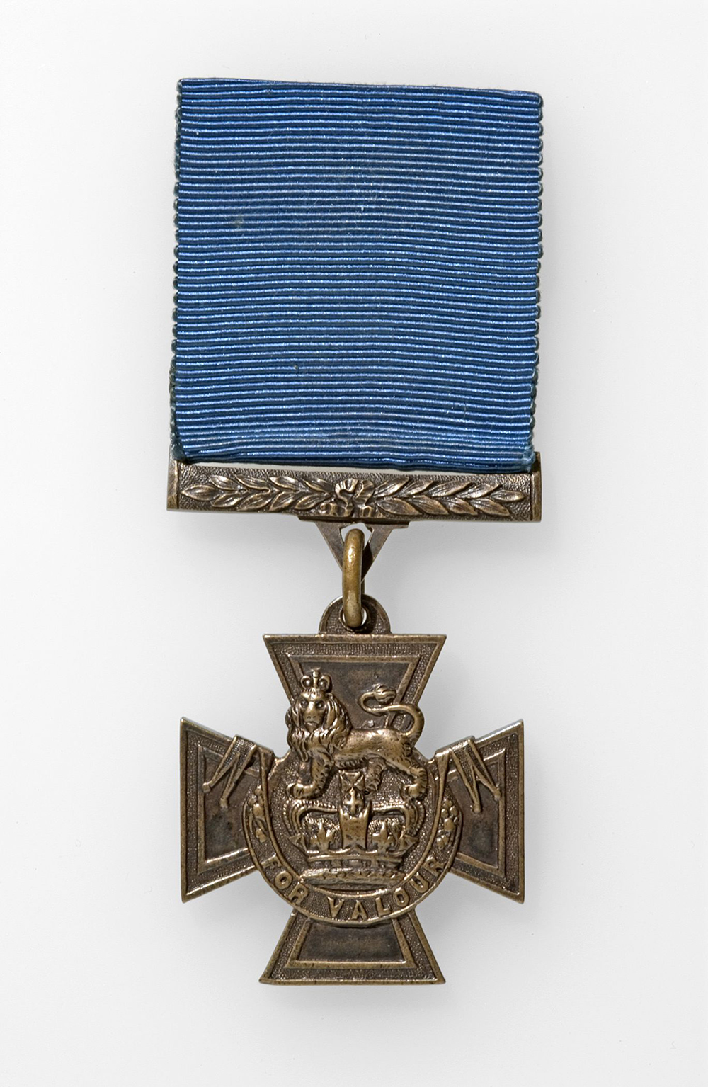 A Victoria Cross brass medal hanging from a royal blue ribbed ribbon.