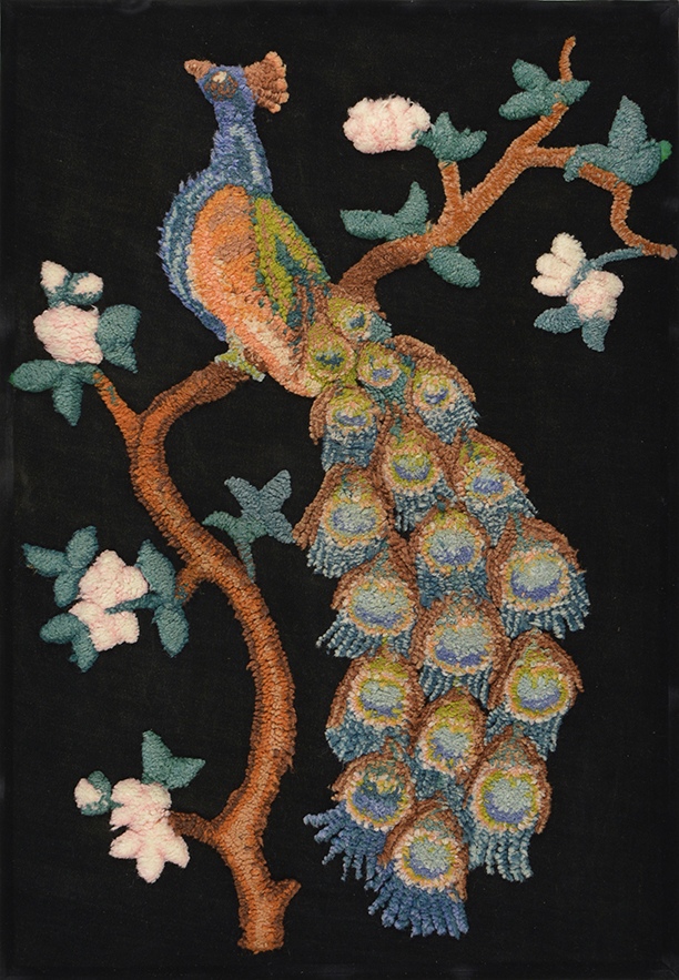 An embroidered colourful peacock sitting on a branch with white flowers and foliage.
