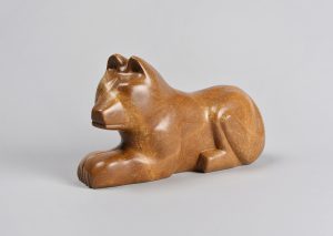 A smooth stylized rust-coloured soapstone carving of a wolf.