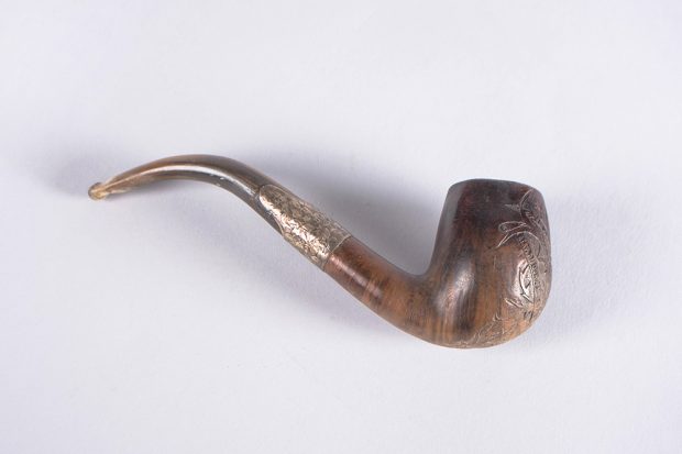 An engraved wooden pipe with a metal filter attaching its bowl and stem.