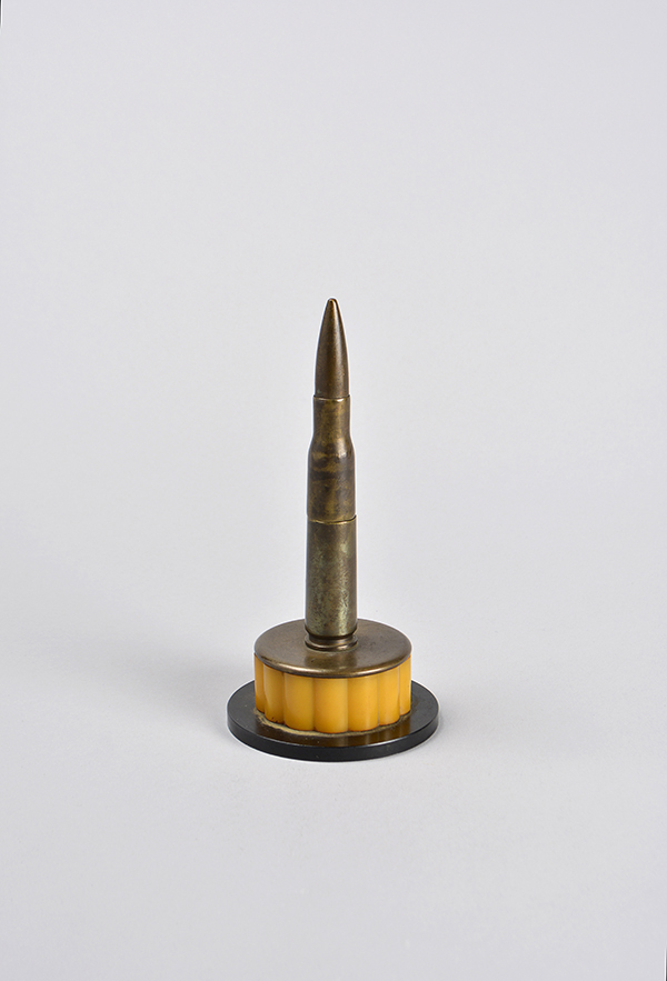 A bullet made into a lighter mounted on a brass and orange plastic bottom.