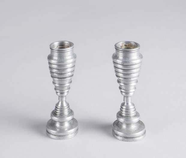 Aluminum candle holders with bevels increasing and decreasing in size.