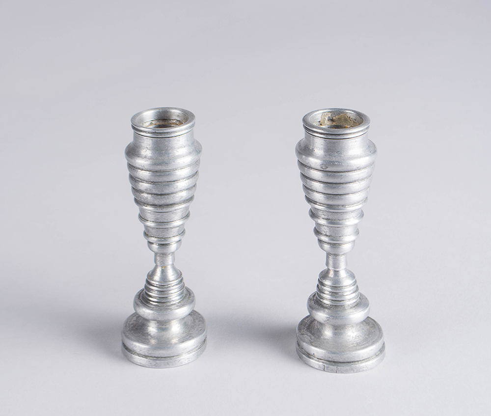 Aluminum candle holders with bevels increasing and decreasing in size.