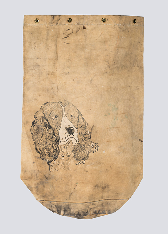 A well-worn tan canvas kit bag with a painted image of a Springer Spaniel on it.