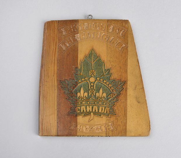 A prepared and finished piece of propeller made into an engraved plaque. There is a green maple leaf on it with a crown and the word “Canada” in the middle.