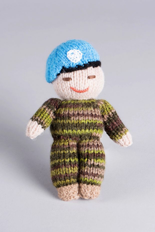 A small knitted doll that is an effigy of soldier in uniform.