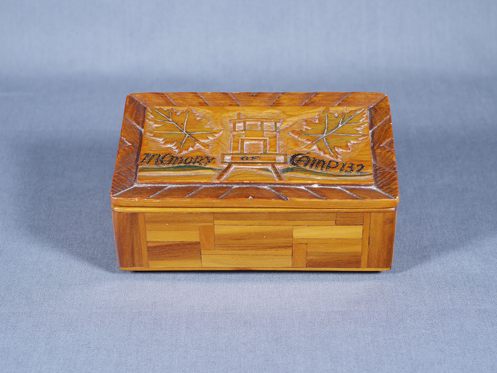 A handmade wooden box with lid embossed with a building flanked by maple leaves on both sides.