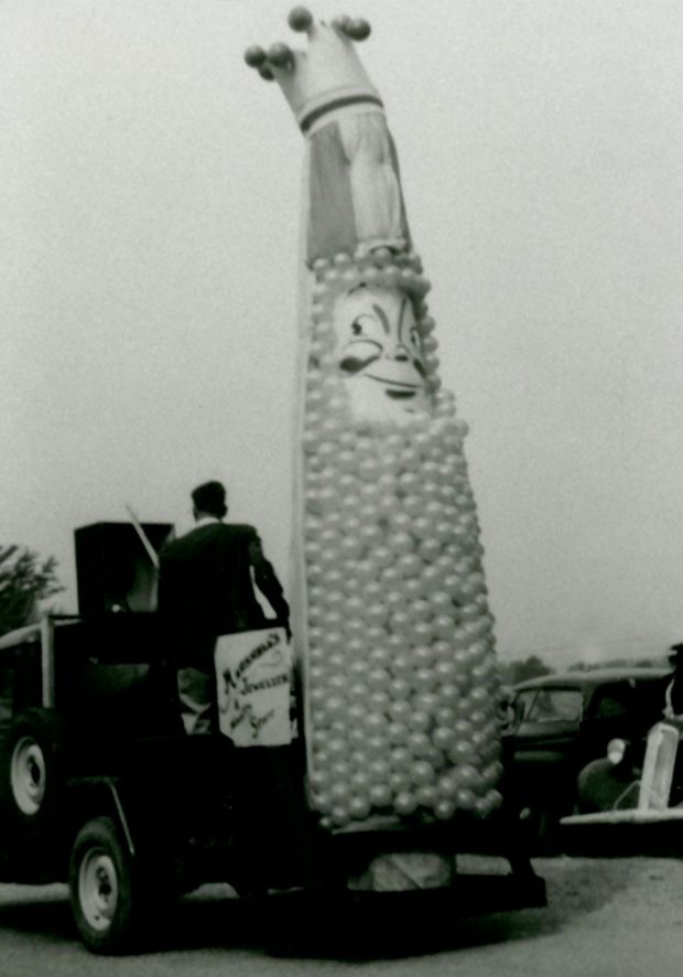 Black and white photograph of the Corn Festival mascot float. The mascot is made up of balloons and has a crown.