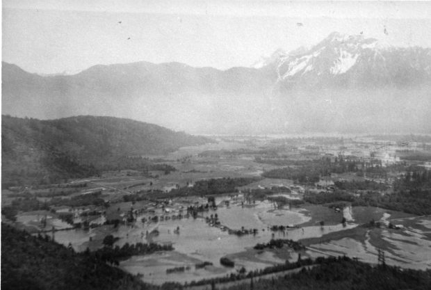 Black and white photograph of flooded fields with mountains in the background.