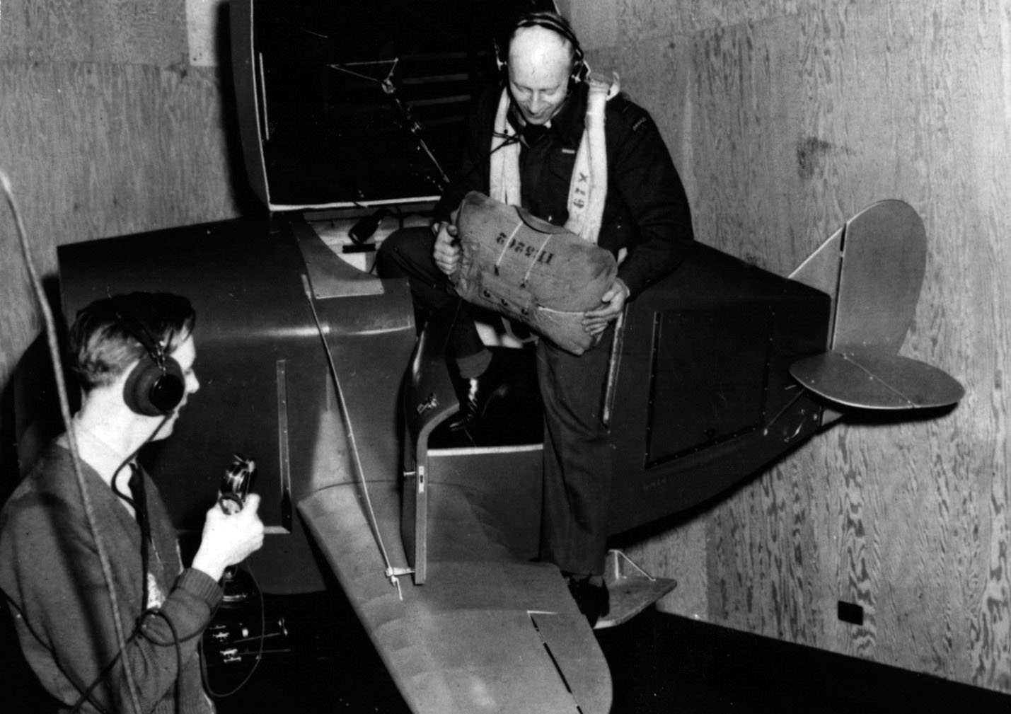 Man exiting model plane while another man watches