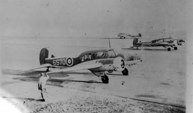 Three twin engine planes on runway with ground crew