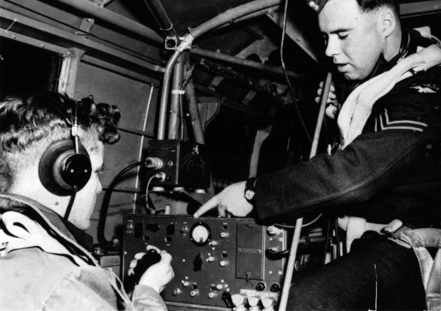 Two young men in military uniforms in aircraft with wireless radio.