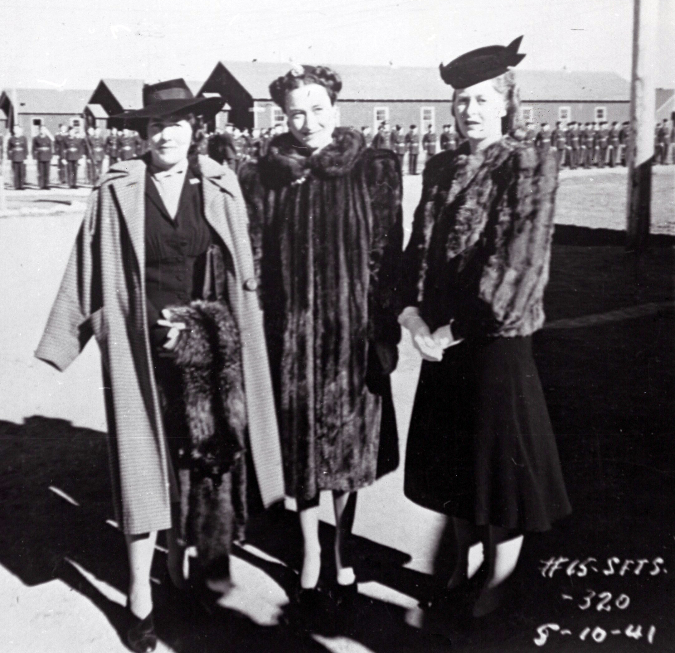three women with military troop in background