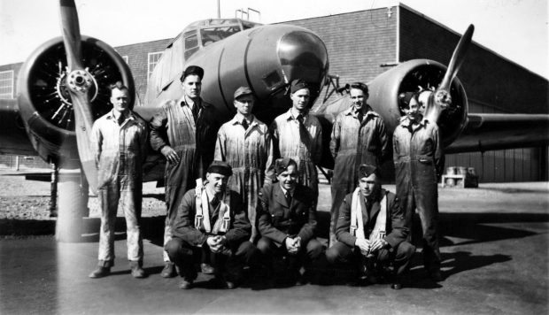 3 airmen and 6 mechanics in front of airplane and hangar