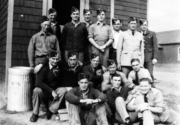 16 airmen and ground crew in front of barracks