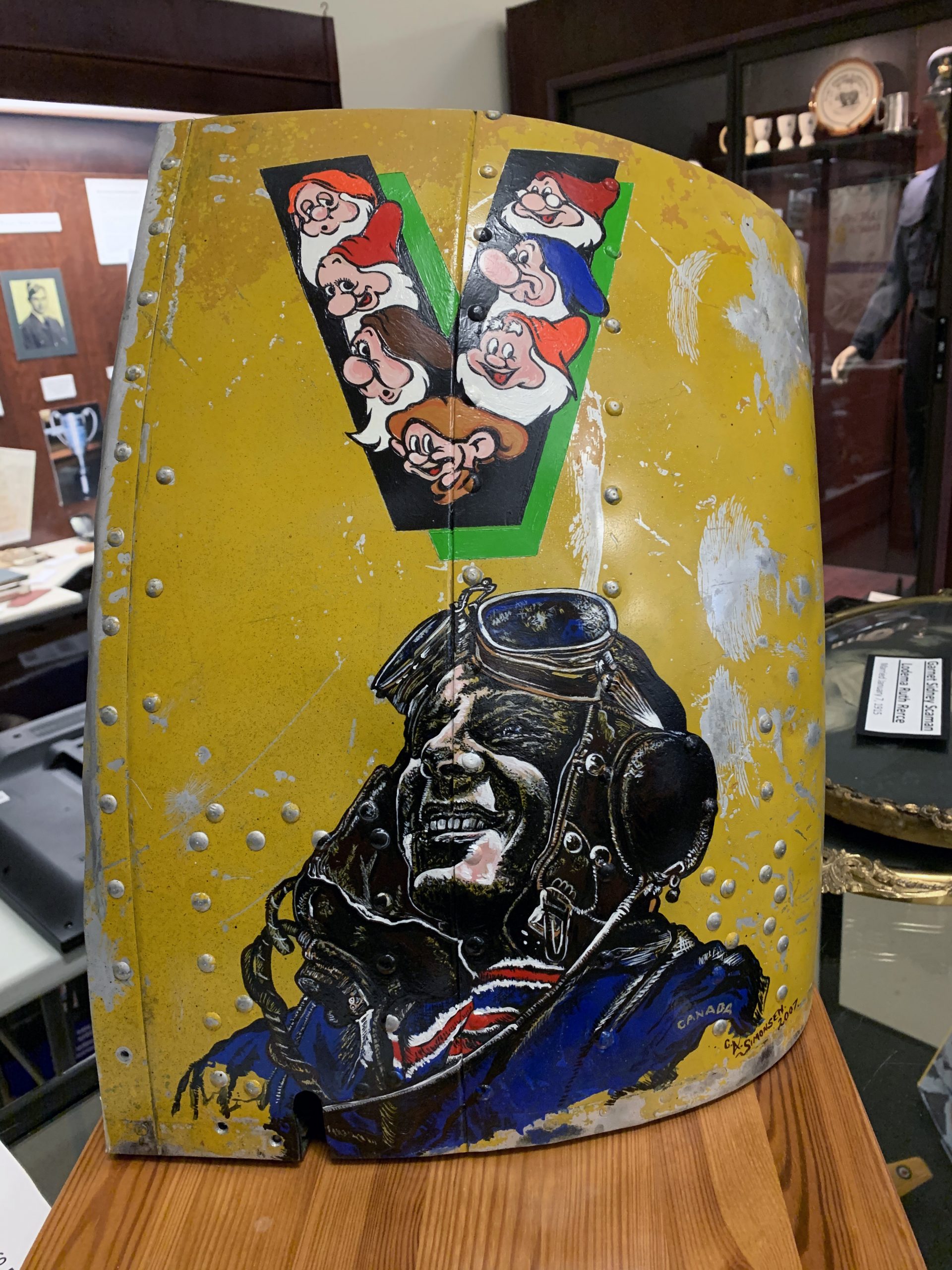 yellow engine cowling piece with two paintings on it