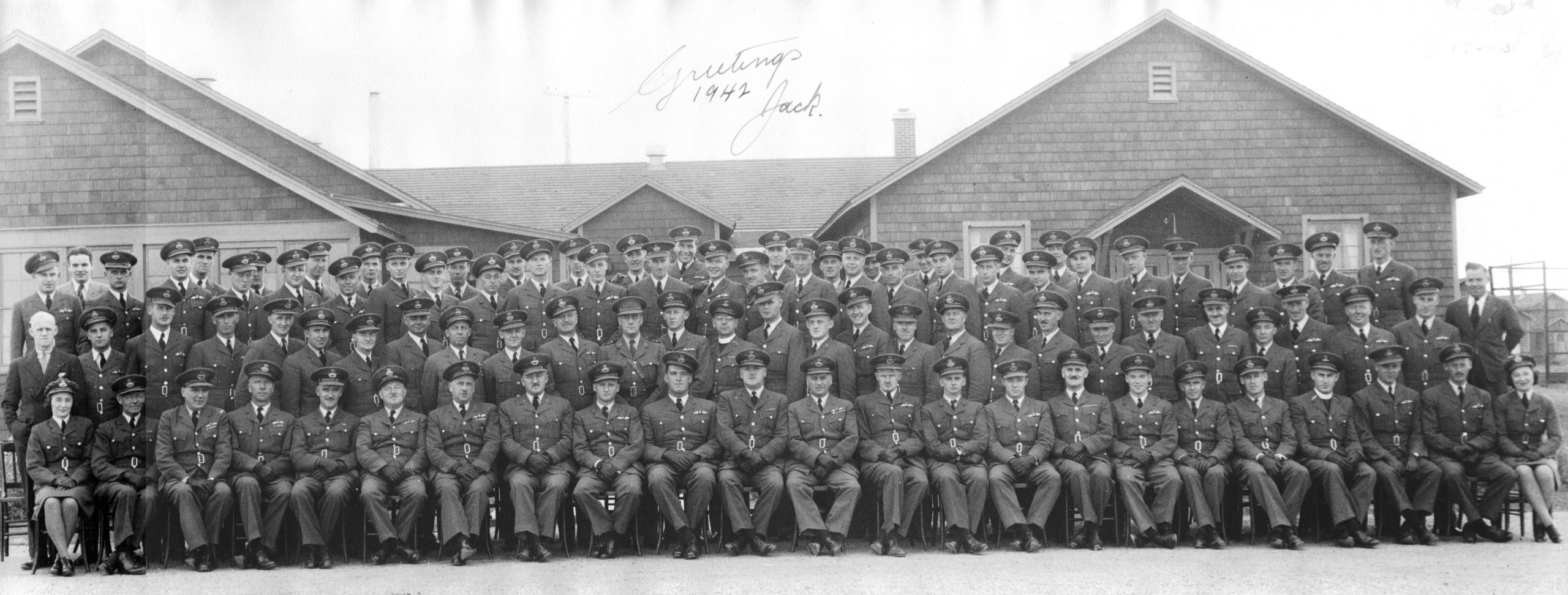 Photo d’un grand groupe de militaires, hommes et femmes, devant le quartier général de la base