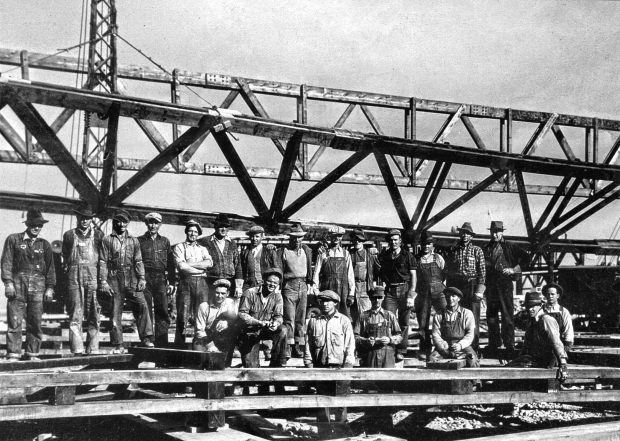 A work crew of 21 men in front of hangar construction site