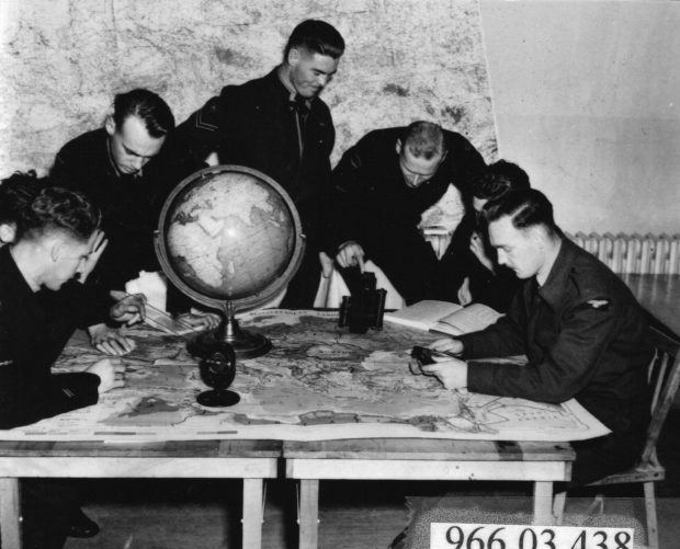 7 airmen looking at maps on table