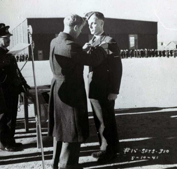 3 men, two in military dress, troops and hangar in background