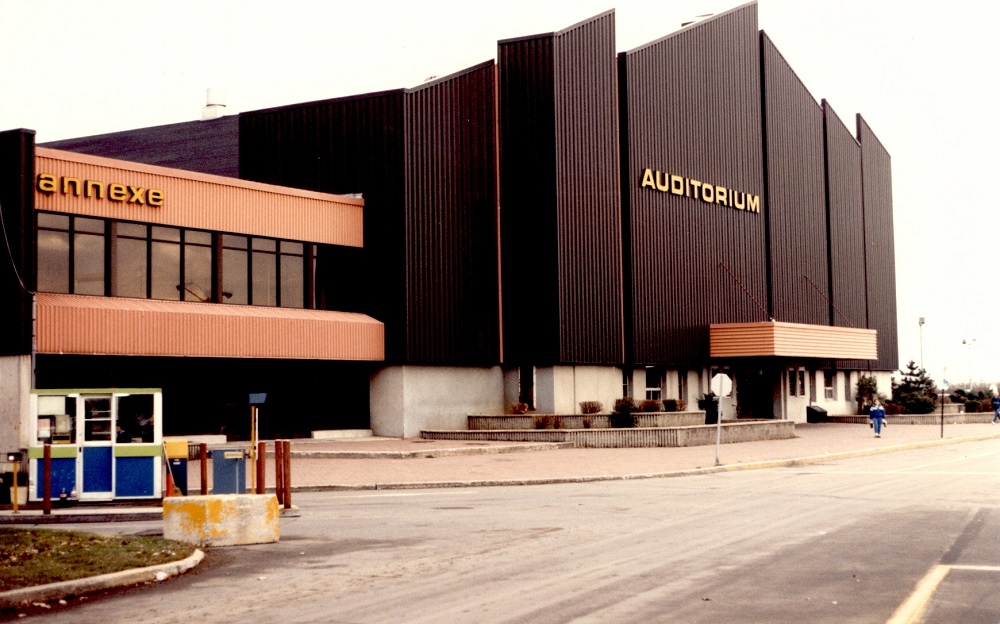 Colour photo showing two buildings: one with a black metal front and the other, orange. "Auditorium" is marked on the black front, and "Annexe" on the orange building.