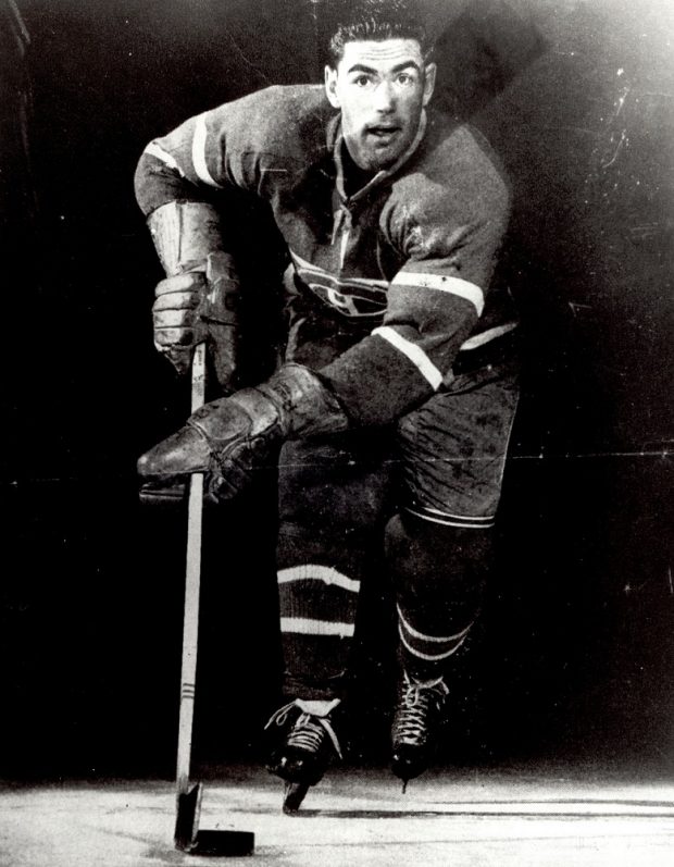 Black-and-white front-view photo of a hockey player, with his equipment, skating in the official Montréal Canadians uniform.