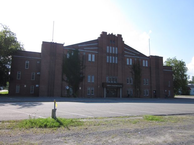 Colour photo showing a red-brick building with the name of the building (Aréna Jacques-Plante) marked on the main entrance.