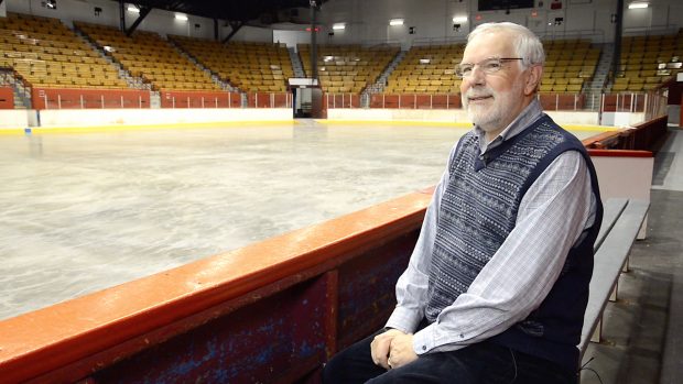 Colour photo of a man seating on a arena bench.