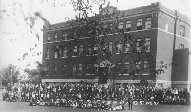 hundred schoolchildren pose in front of the Academy