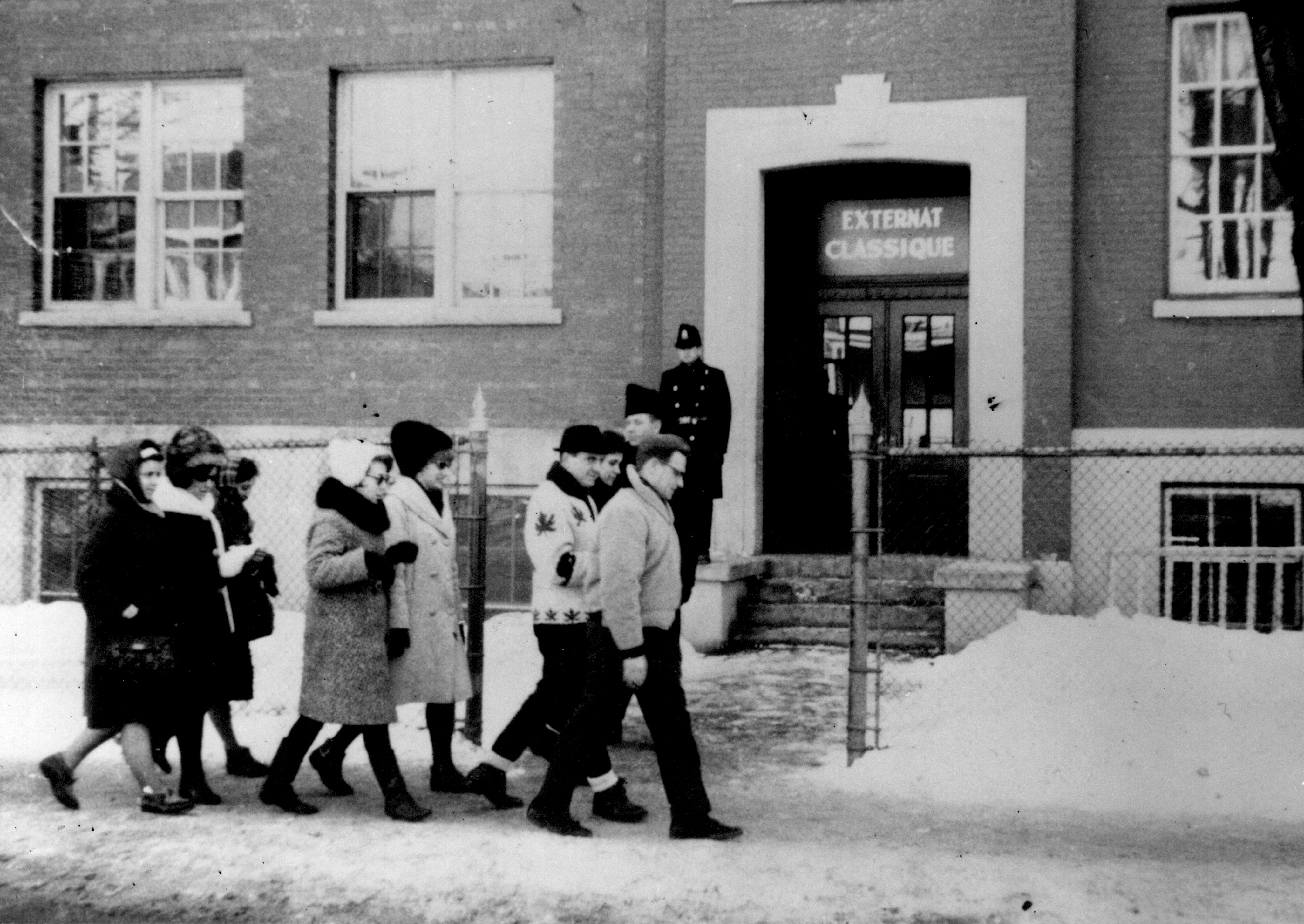 Several wrapped passers walk in front of the classic day school