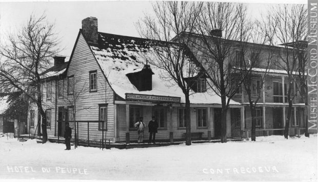 This is a picture of the Hôtel du peuple, taken around 1910. We can see that a second structure, consisting of three floors, has been attached to the white wooden house on which the sign has been affixed. The sign reads: Hôtel du Peuple F de S Gervais — Prop.