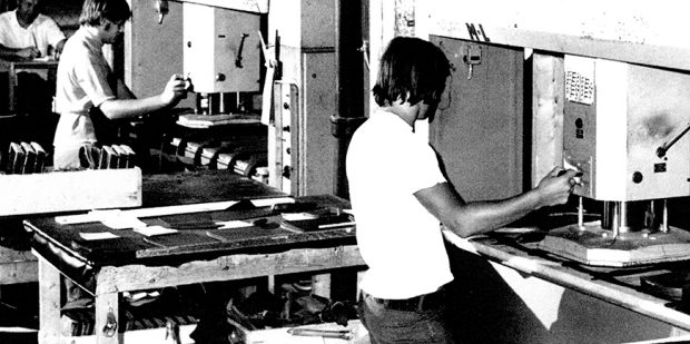 In this picture, we see two workers operating cutting presses. They are Marcel Gagné on the left and Martial Gervais on the right. In the background to the left, we catch a glimpse of Gilles Tétreault, Trimming Department Foreman, sitting at his desk.