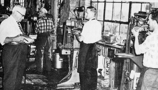 The photo shows Henri Bergeron, manager of operations at Lafayette from 1945 to 1960, inspecting a shoe being crafted at the assembly stage. Three workers, Jos Geoffrion, Jean-Paul Piché and Maurice Beauregard, are set up in front of their machines.