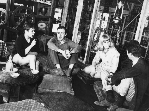 Black and white photo of Raymond Lévesque and three other people sitting on cushions in La Butte.