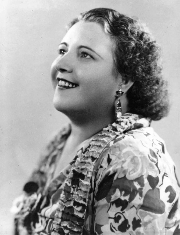 Black and white photo of La Bolduc in a floral dress looking up to the sky.